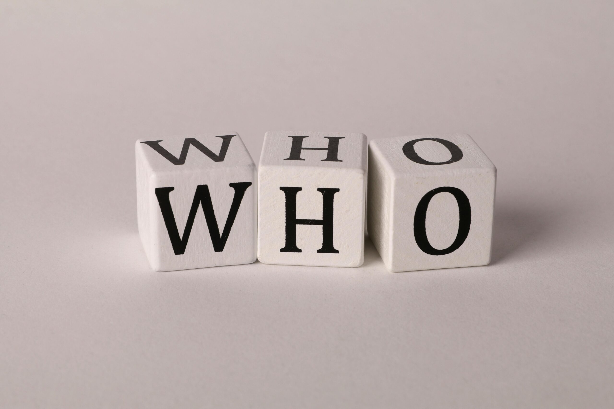 Three wooden alphabet blocks spelling 'WHO' on a white background, perfect for word games or educational content.